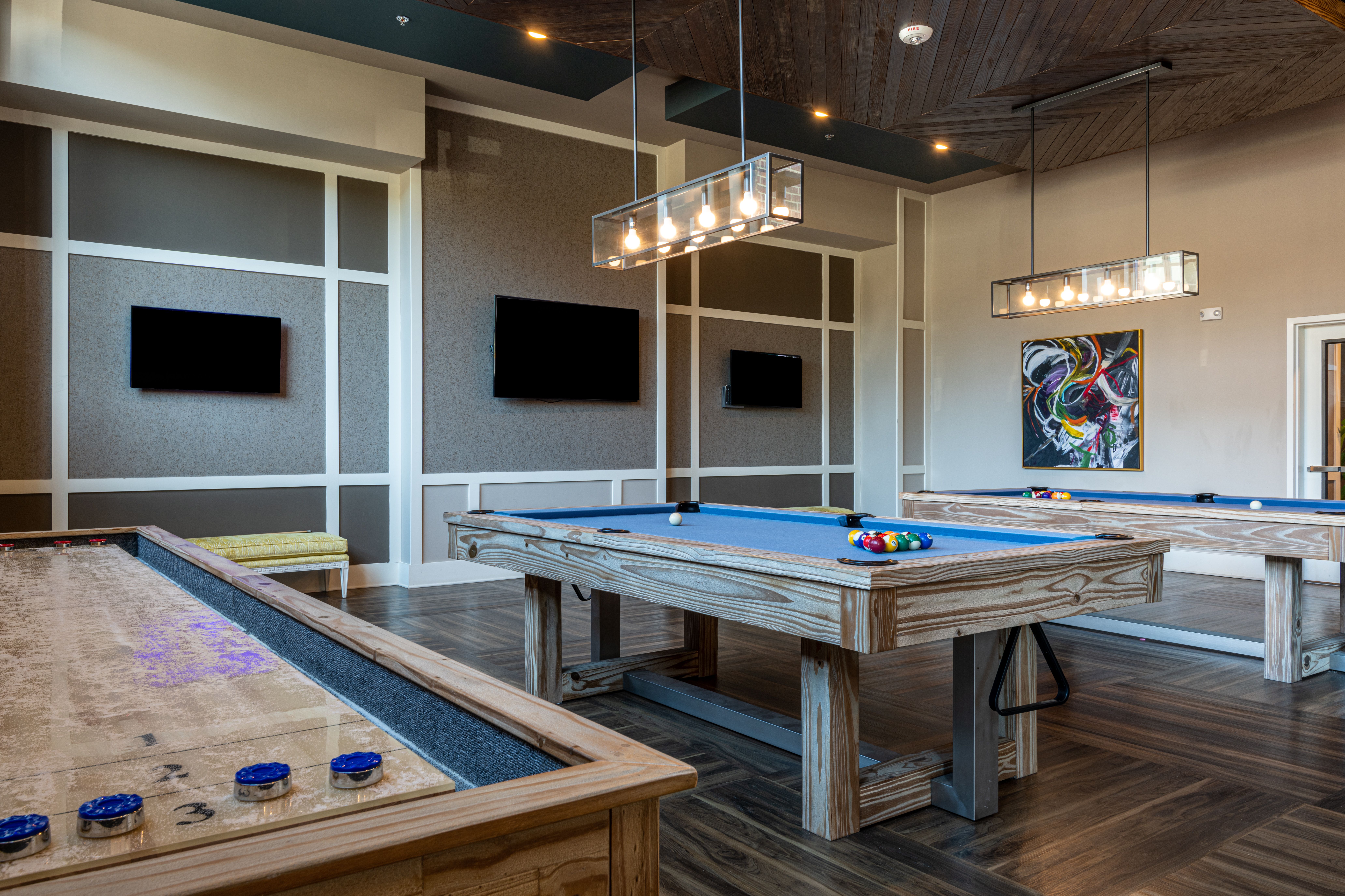 Billiards table and shuffleboard table inside game room amenity at Carraway Village Apartments in Chapel Hill, NC