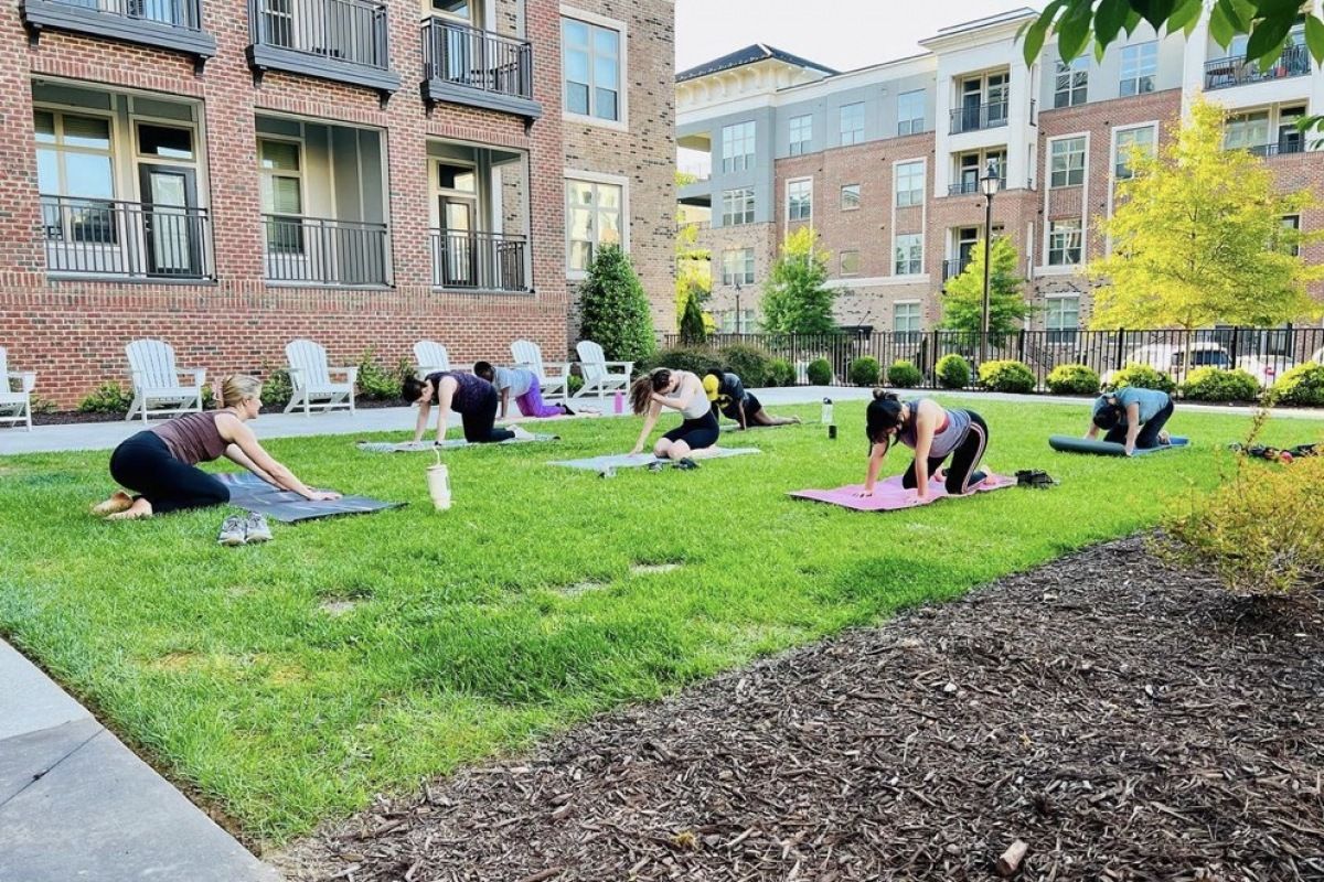 Outdoor lawn outside of Carraway Apartments with a yoga class occurring