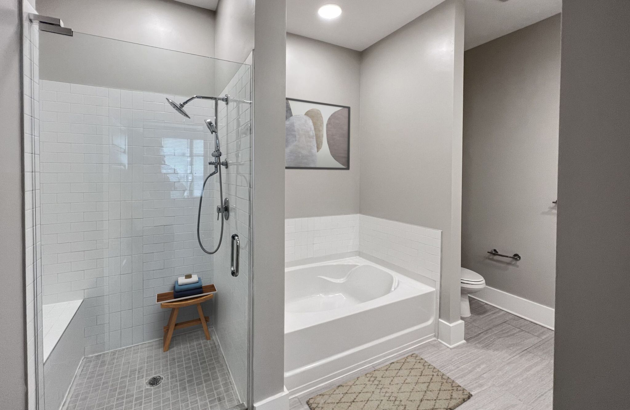 Luxury apartment bathroom with glass-enclosed shower with tile bench and large garden style soaking tub