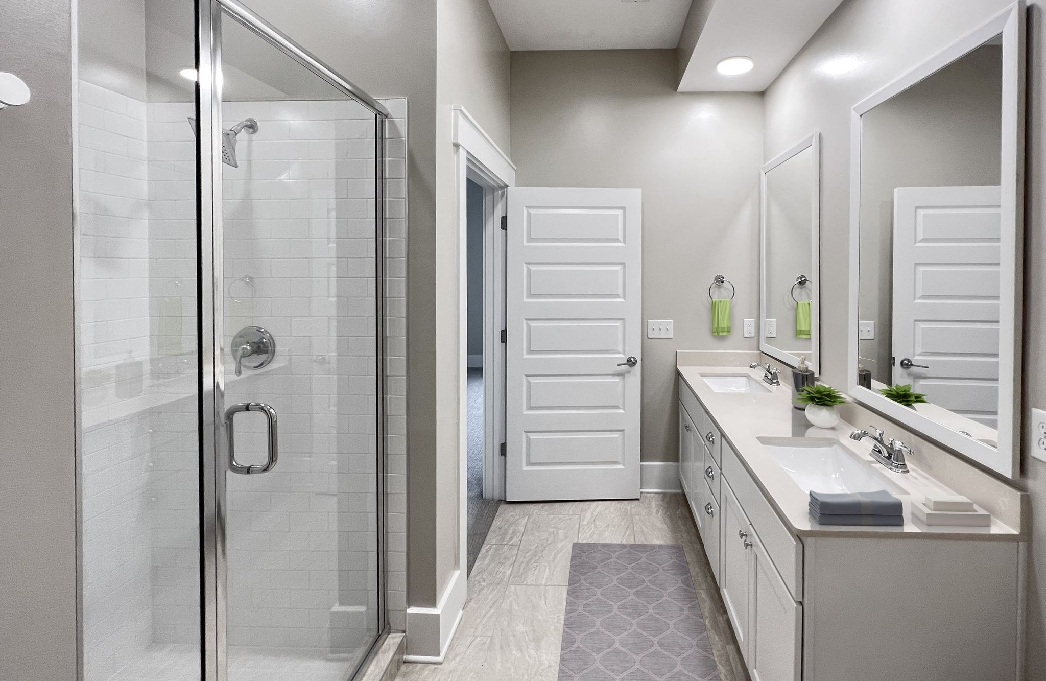 Spacious apartment bathroom with glass-enclosed shower, rain showerhead, and double vanities