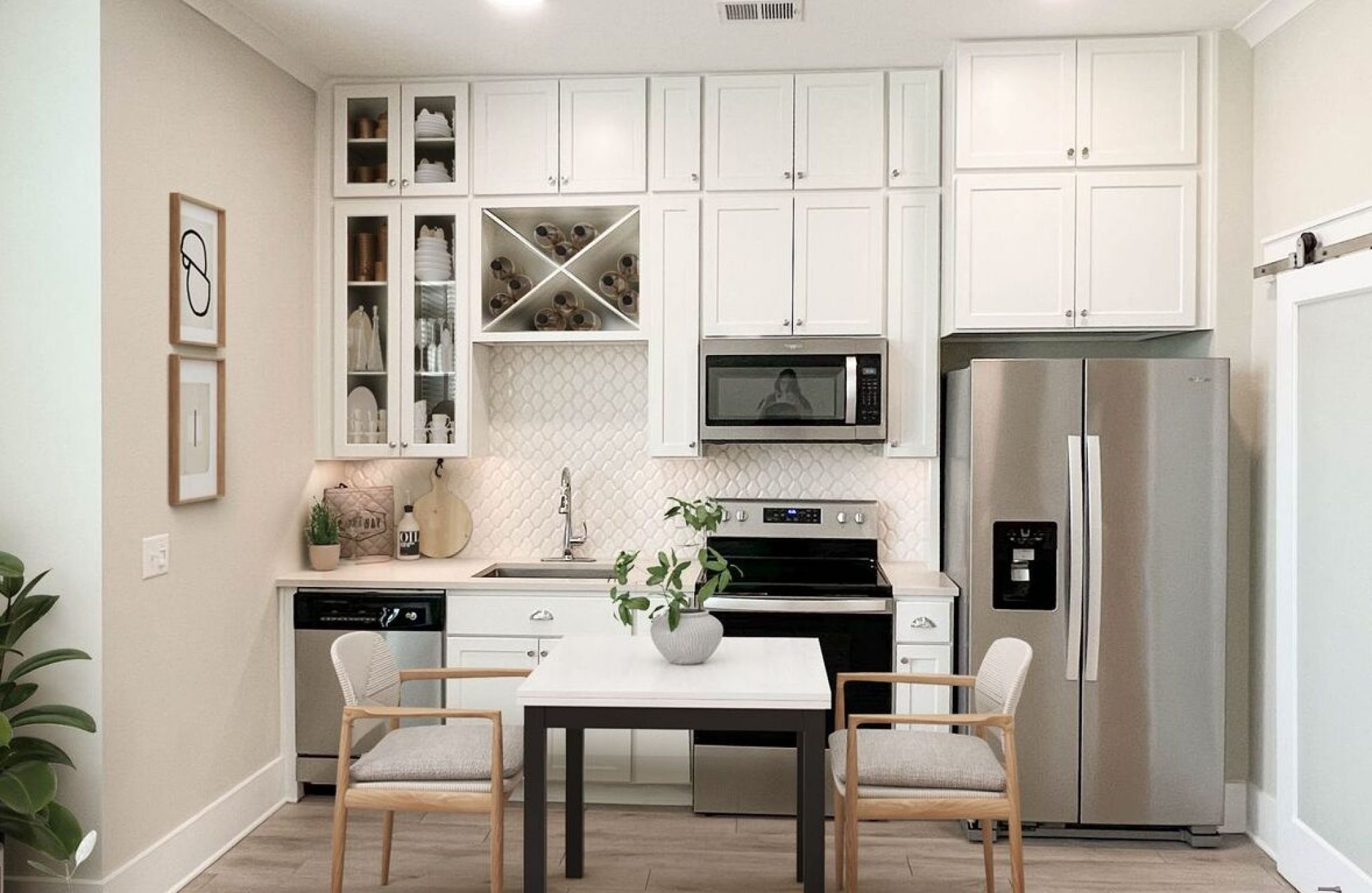 Studio apartment kitchen with stainless steel appliances, built-in wine storage, and small dining table
