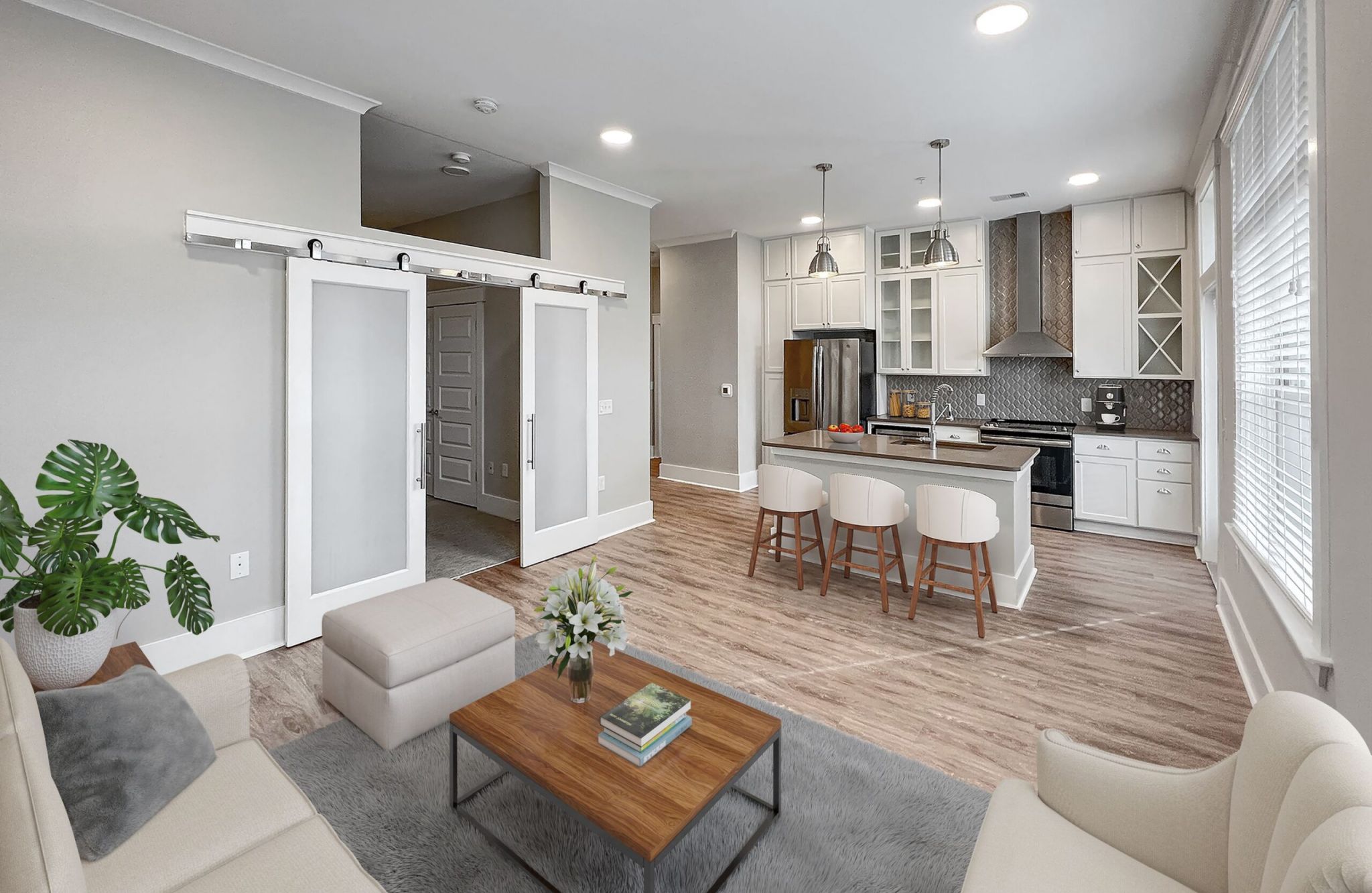 Beautiful apartment living and kitchen area with luxury hard-wood plan flooring, sliding barn doors, and huge windows