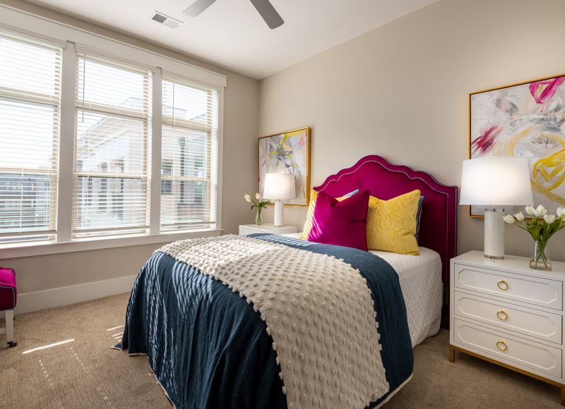 Apartment bedroom with comfy bed, ceiling fan, carpet, and large windows