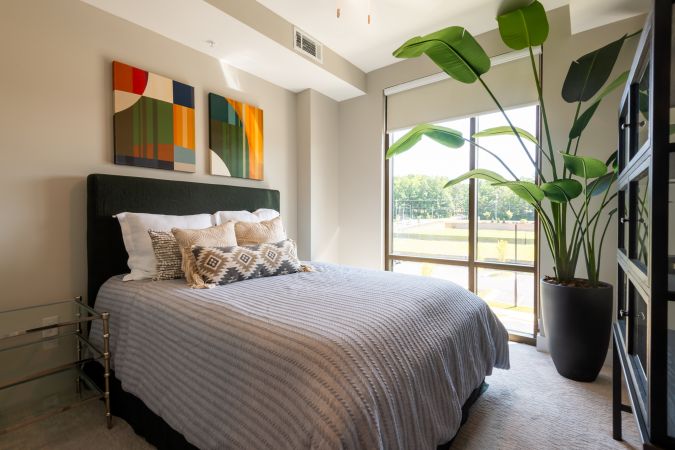 Open concept layout in luxury apartment showing a large floating kitchen island, large sink, floor to ceiling windows, and a large living room space