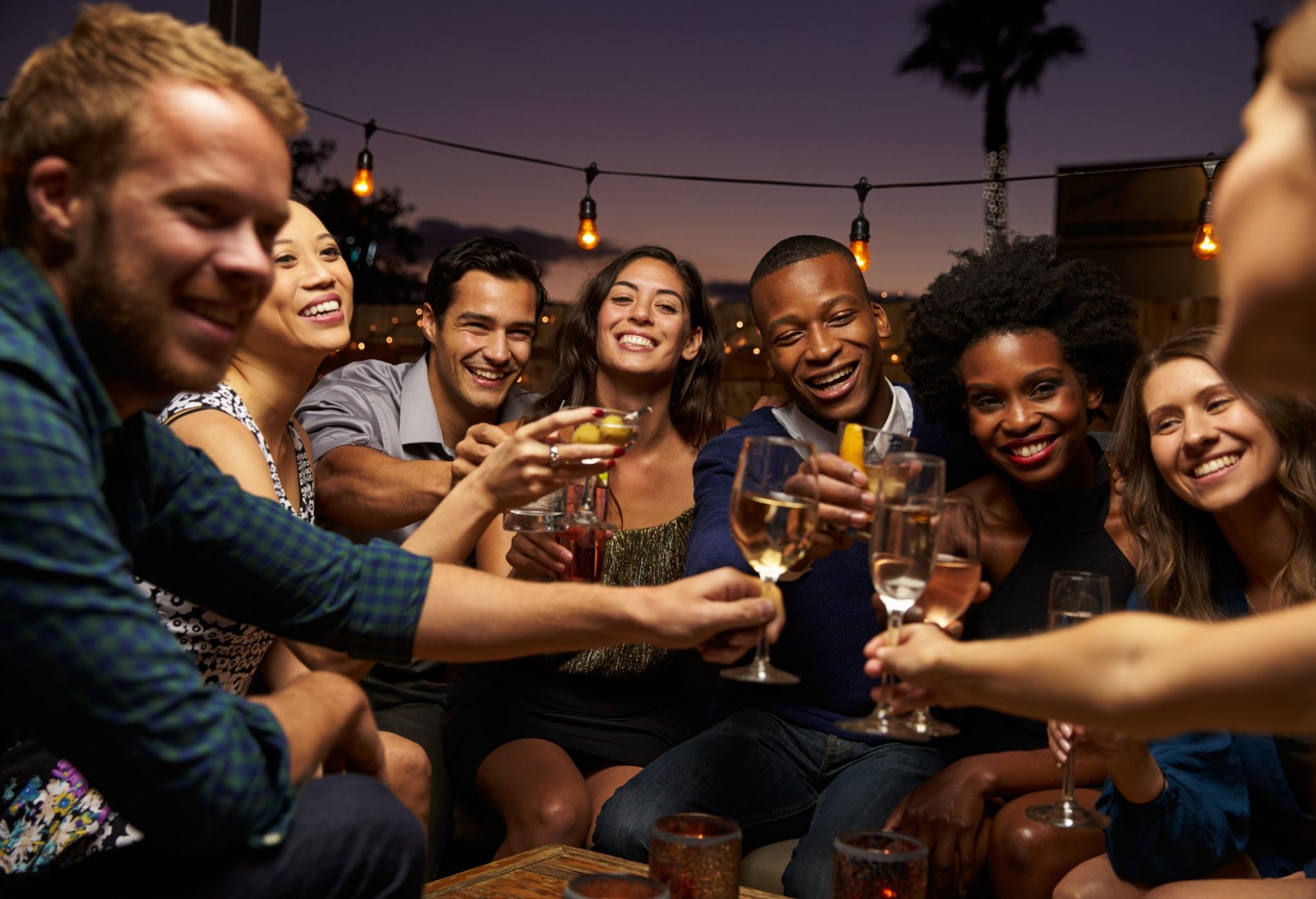 Group Of Friends Enjoying Night Out At Rooftop Bar