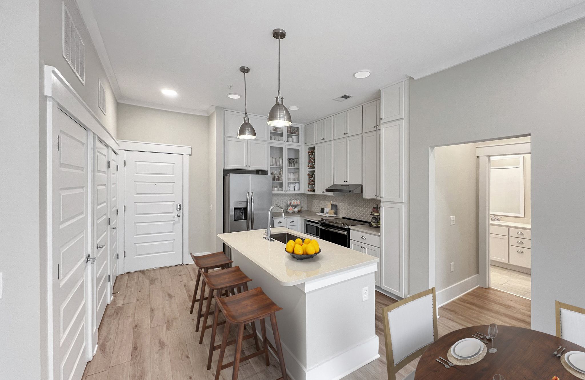 Luxury apartment kitchen with floating kitchen island, pendant lighting, ample cabinet storage, and built-in wine storage