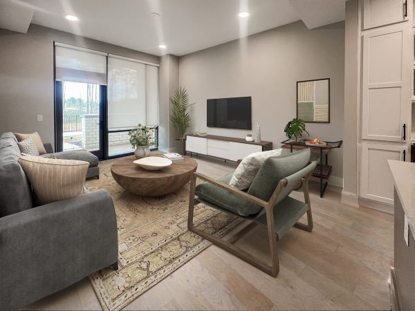Open concept layout in luxury apartment showing a large floating kitchen island, large sink, floor to ceiling windows, and a large living room space